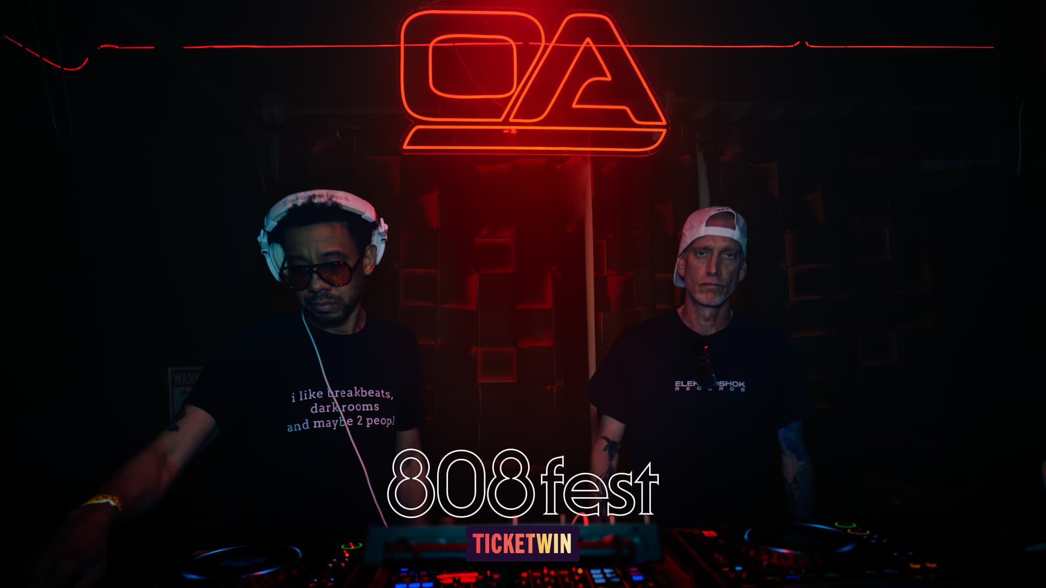 Two DJs behind the decks under the venue neon